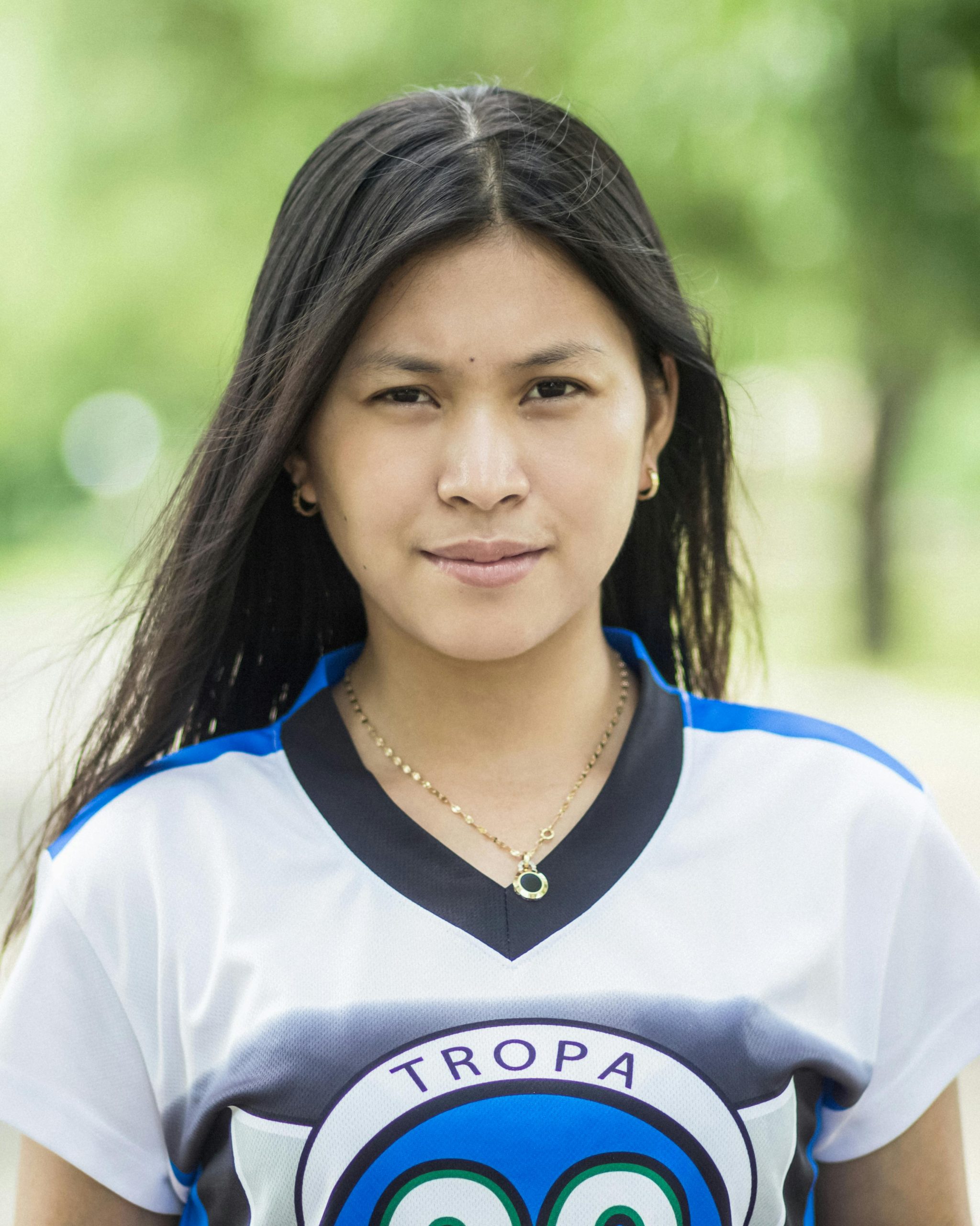 Close-up portrait of a smiling young woman outdoors in casual wear.